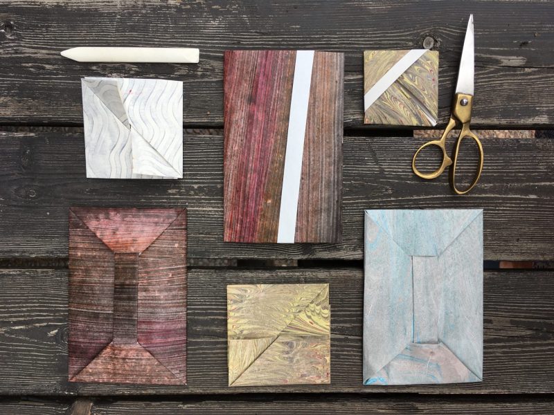 Origami envelopes, a bone folder and brass-handled scissors